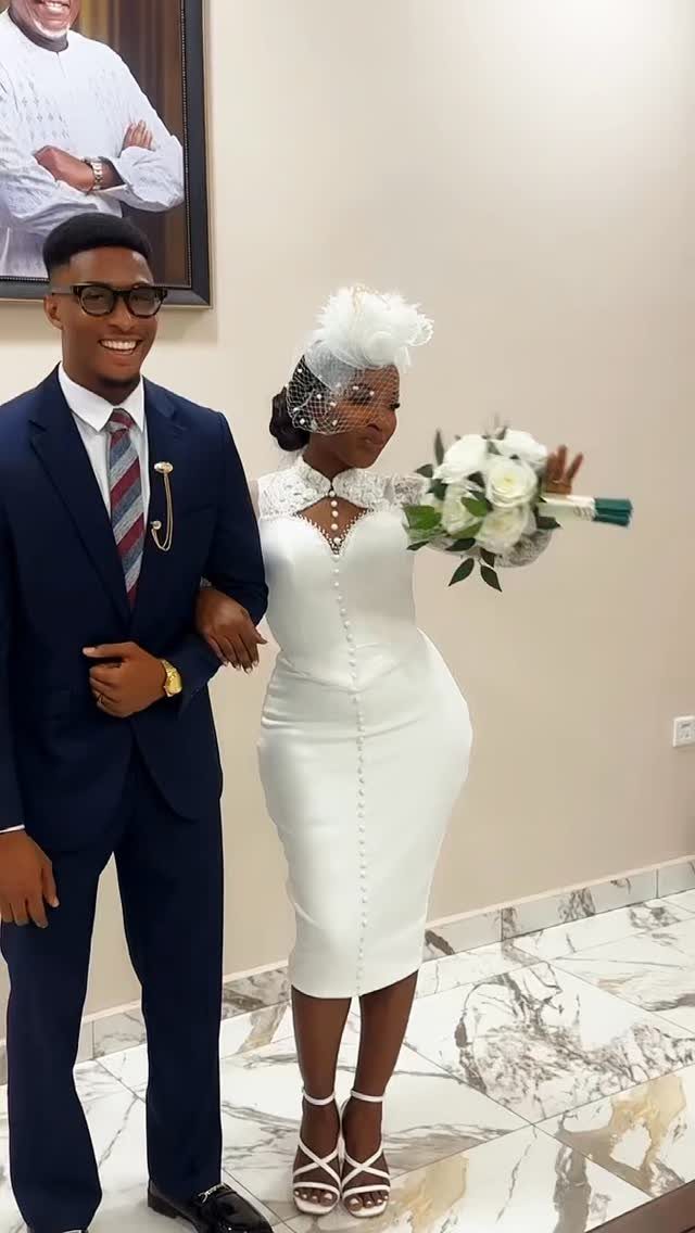 Couple in wedding attire, woman wearing a white dress and feathered fascinator.