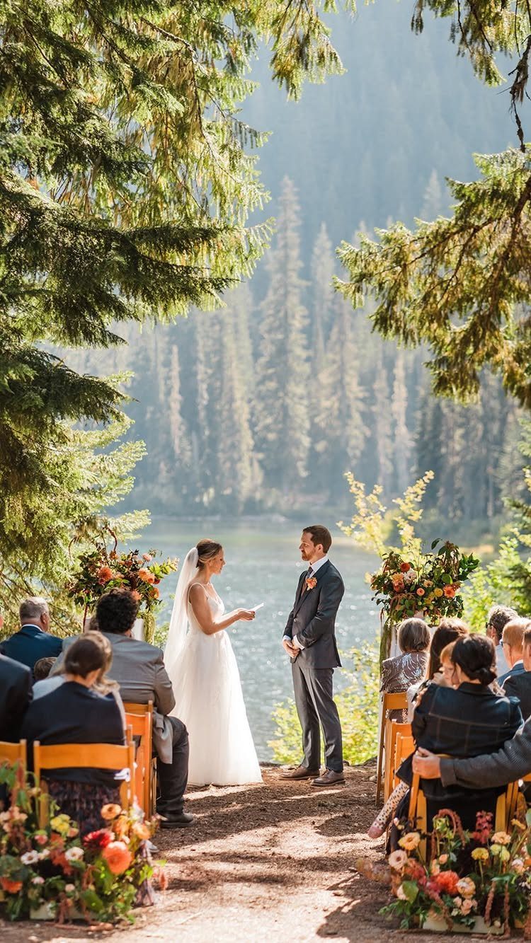 Bride and groom facing each other during an outdoor wedding ceremony in a forest.