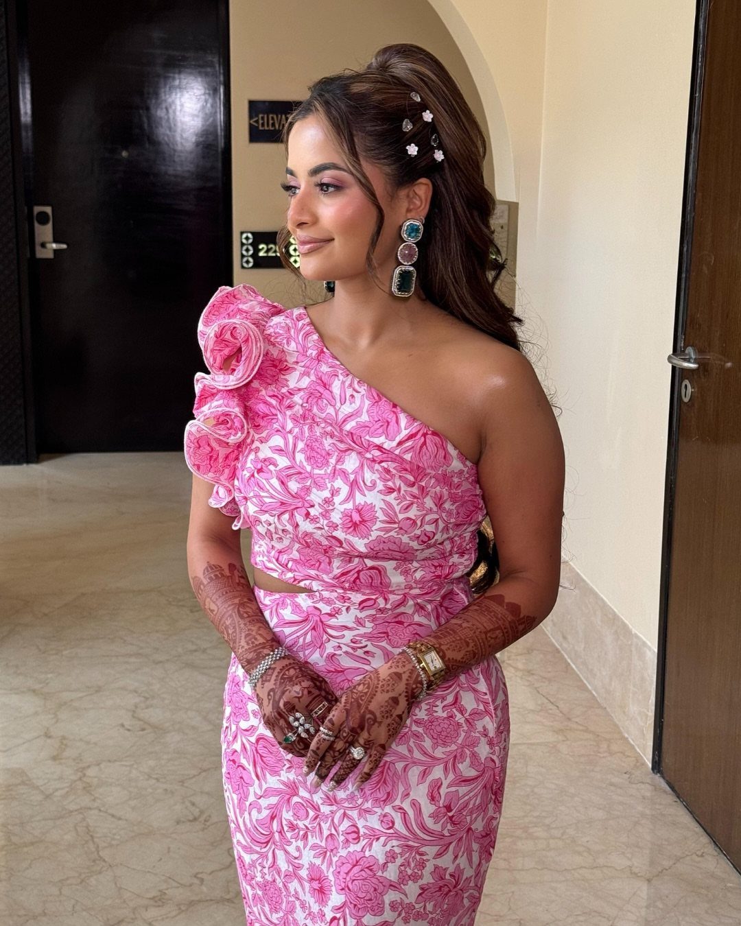 6 Side Ponytail Wedding Hairstyles for Every Bridal Look 6 Woman with a high side ponytail and floral pins wearing a pink floral dress.