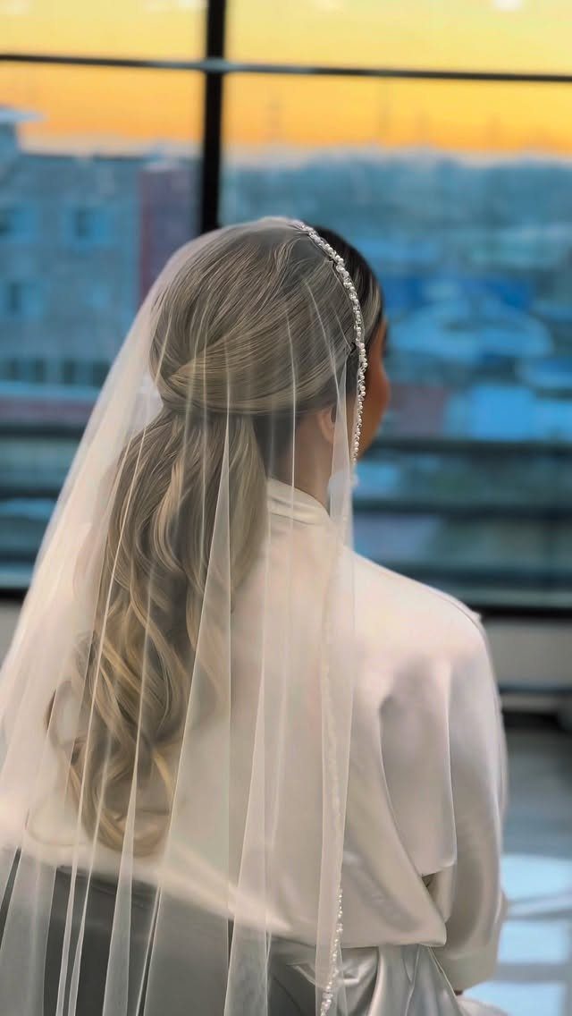 6 Side Ponytail Wedding Hairstyles for Every Bridal Look 5 Woman with blonde hair in a side ponytail wearing a bridal veil and robe.