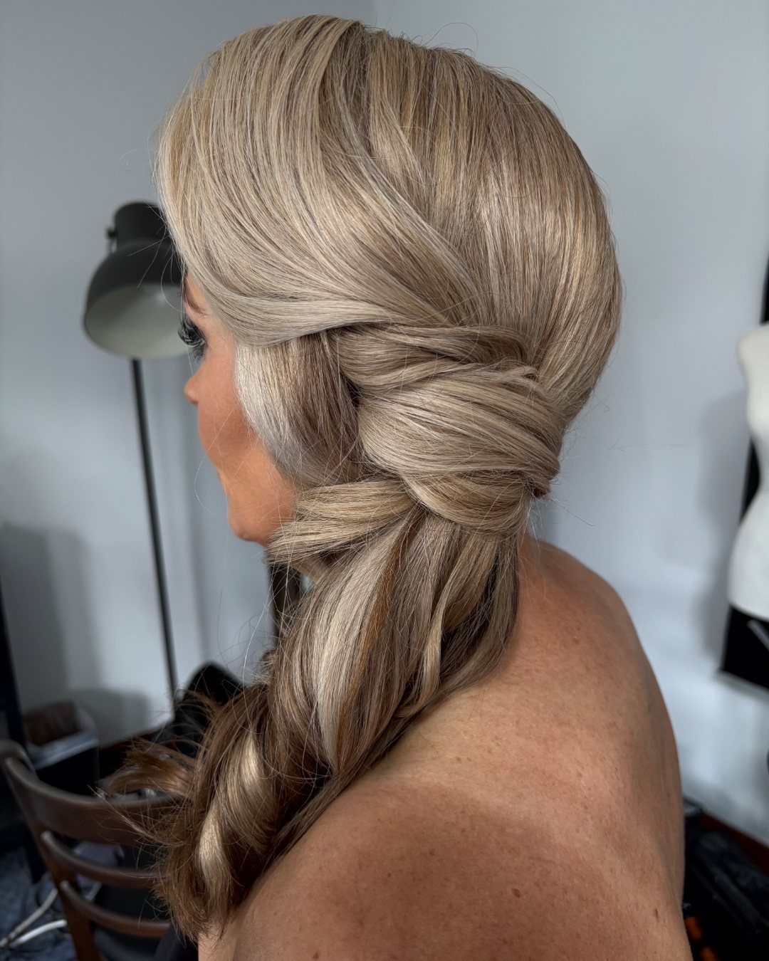 6 Side Ponytail Wedding Hairstyles for Every Bridal Look 3 Blonde woman with a textured side ponytail featuring a thick twisted braid.