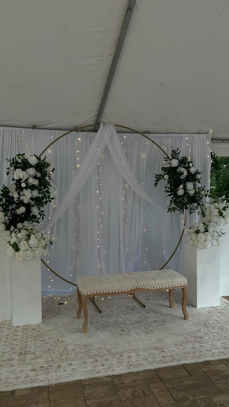 Gold circular hoop with sheer white fabric and fairy lights and white flowers.
