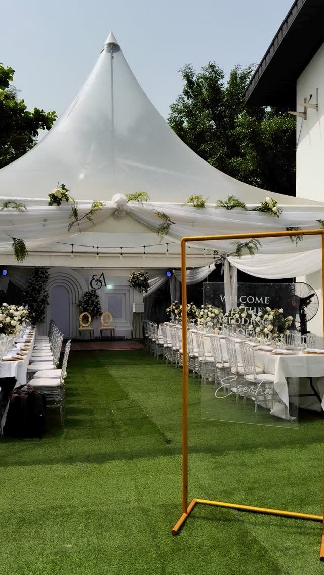 White event tent with dining tables and floral decor on a green lawn