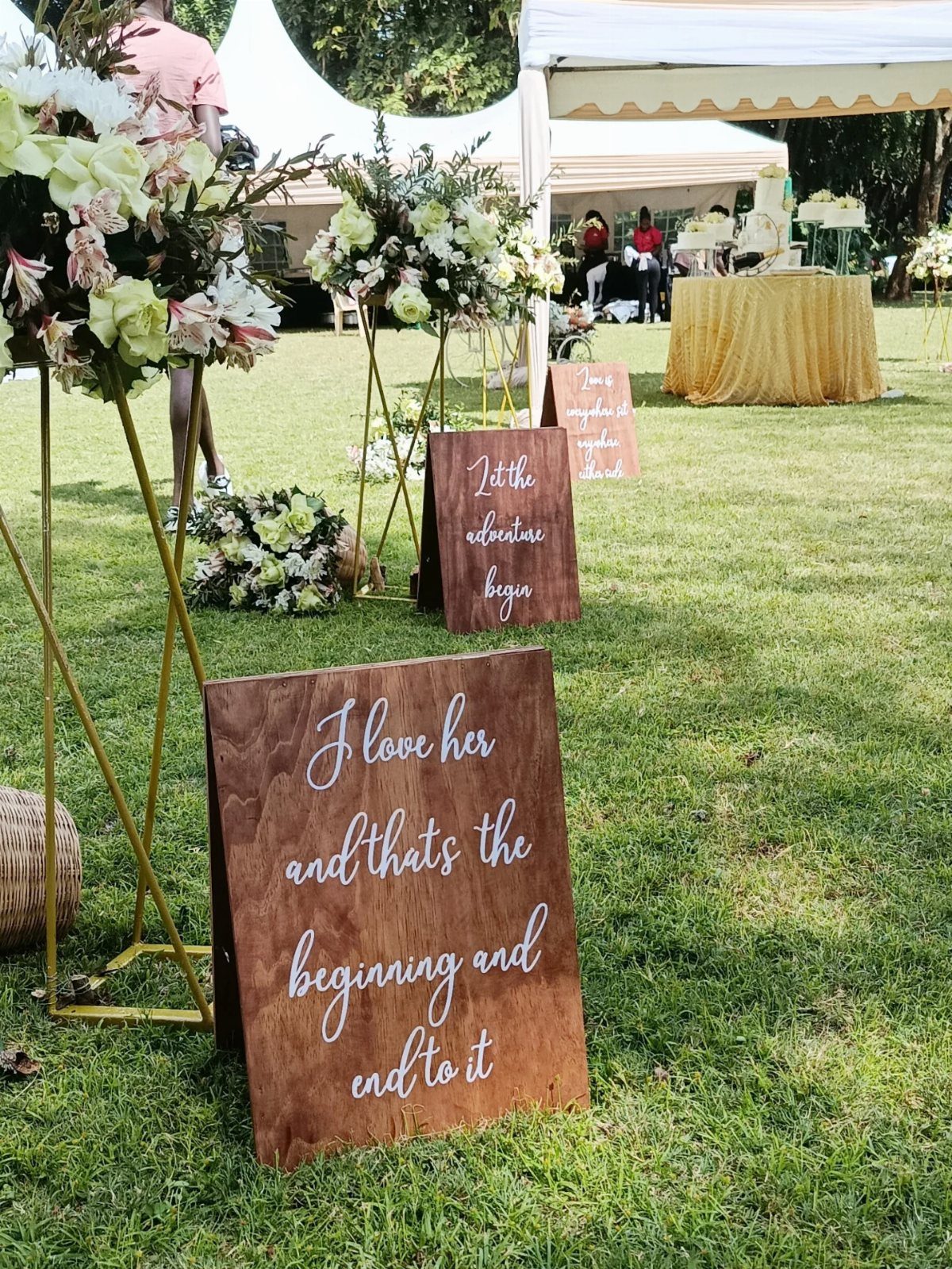 Wooden wedding signs with white cursive text on a grassy outdoor lawn