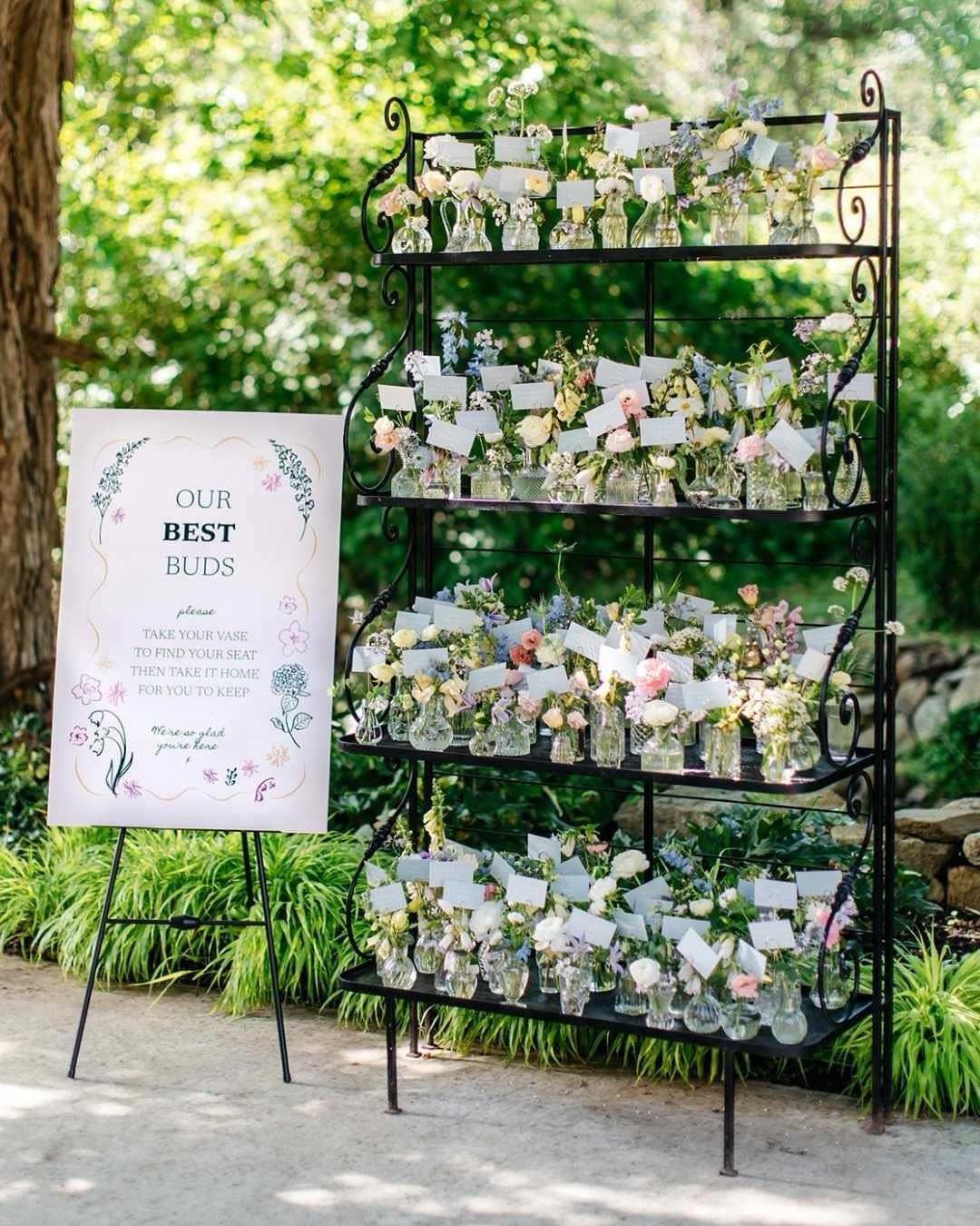 Floral arrangement on a black shelf with a sign reading Our Best Buds.