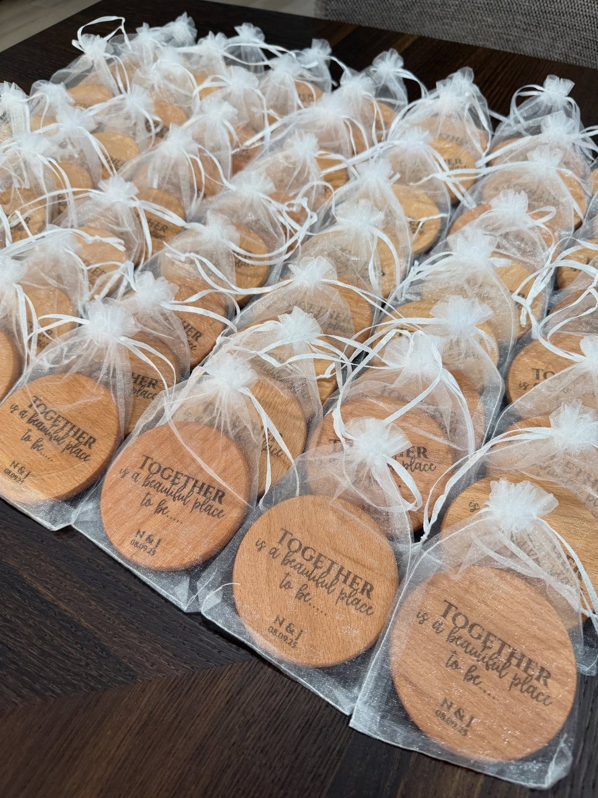 Round stamped cookies in white mesh bags arranged on a dark wooden table.