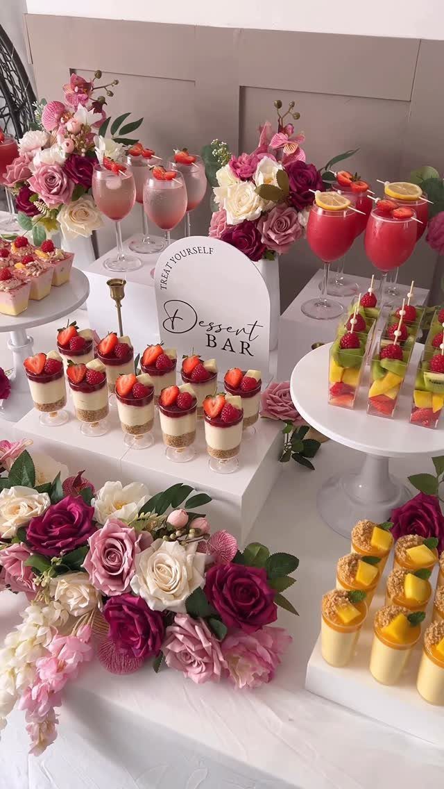 Dessert bar with strawberry and mango treats, pink drinks, and rose floral arrangements.