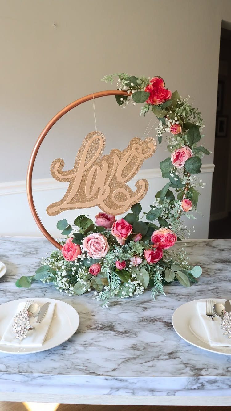 Floral hoop centerpiece with pink roses and gold Love sign on marble table