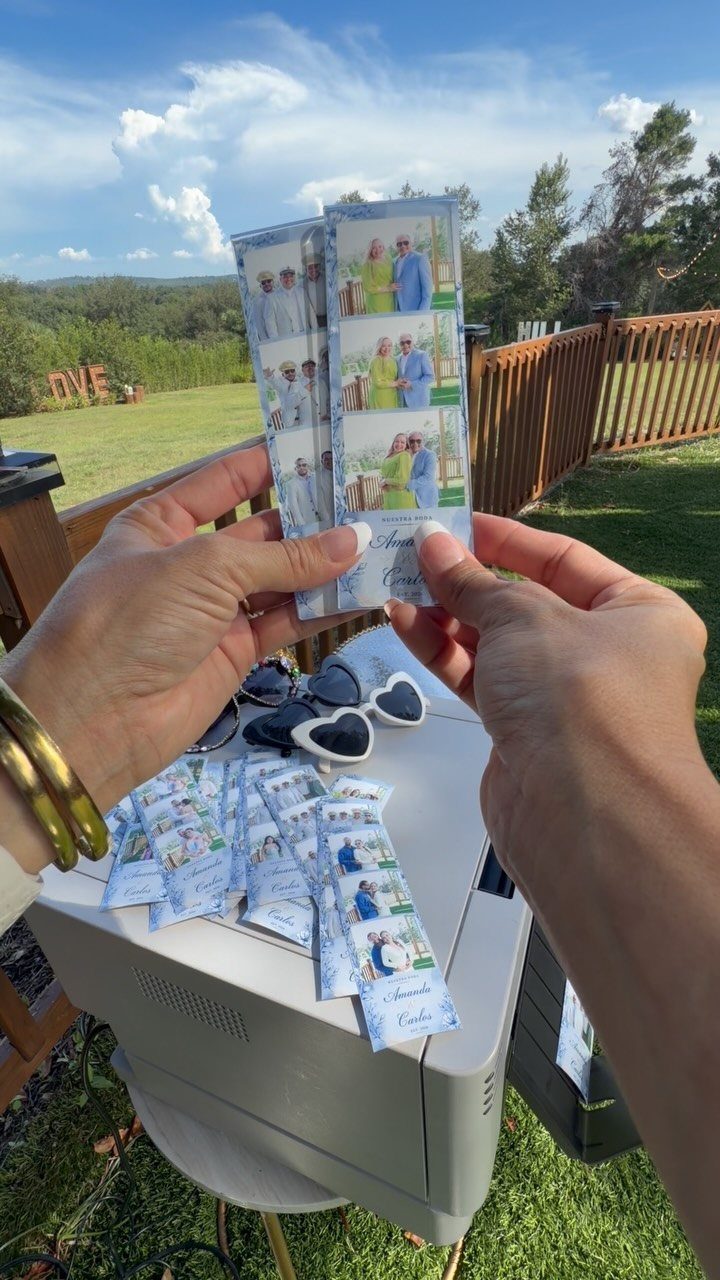 Photo booth strips of a couple held over a white printer outdoors.