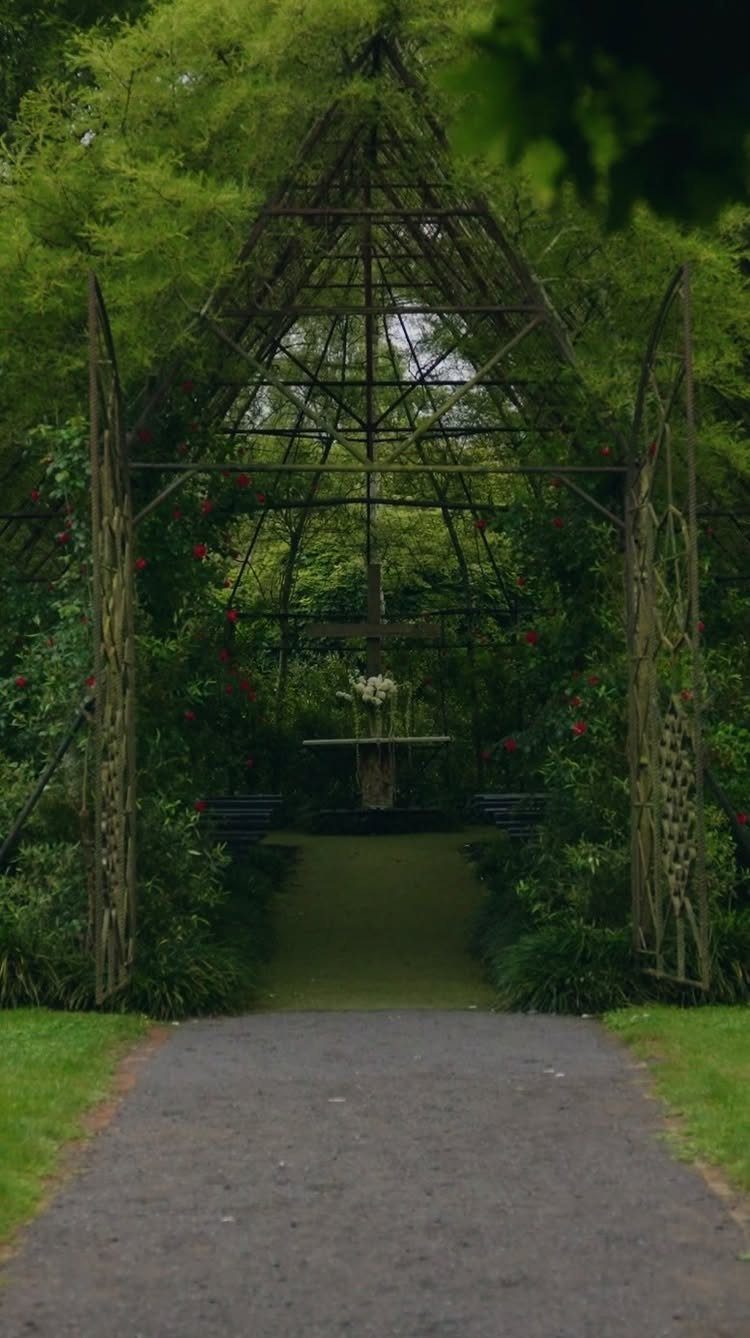 Overgrown metal garden gazebo with a floral altar at the end of a path