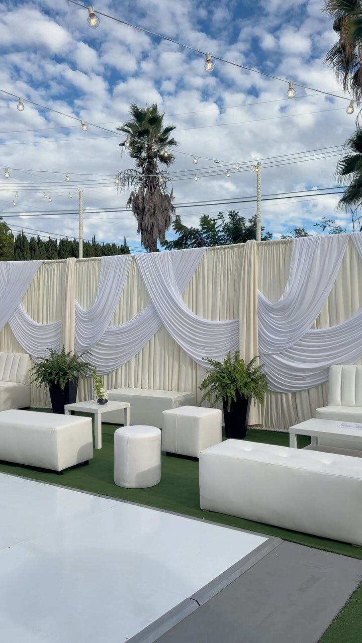 15 Small Wedding Ideas for 50 Guests, From Backyards to Parks 4 Outdoor wedding lounge area with white furniture, draped backdrops, and overhead string lights.