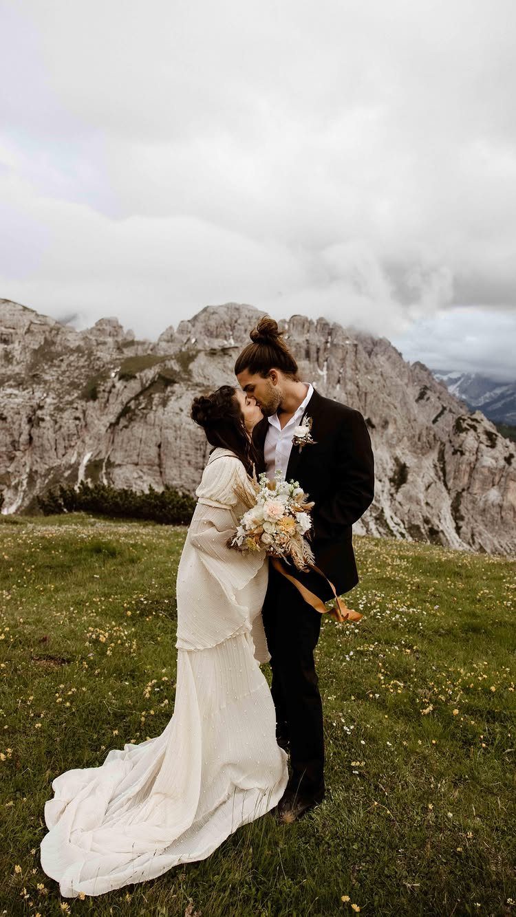 15 Small Wedding Ideas for 50 Guests, From Backyards to Parks 6 Bride and groom kissing in a mountain meadow during a destination wedding ceremony.