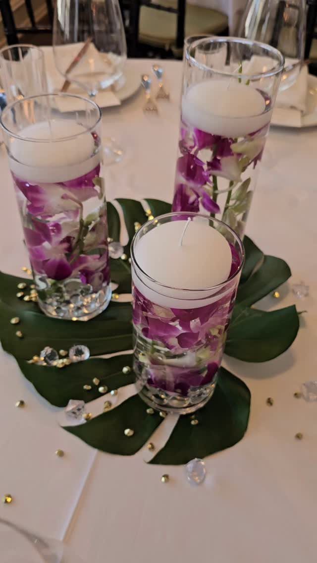 15 Small Wedding Ideas for 50 Guests, From Backyards to Parks 14 Floating white candles with purple orchids in glass cylinders on a tropical leaf.