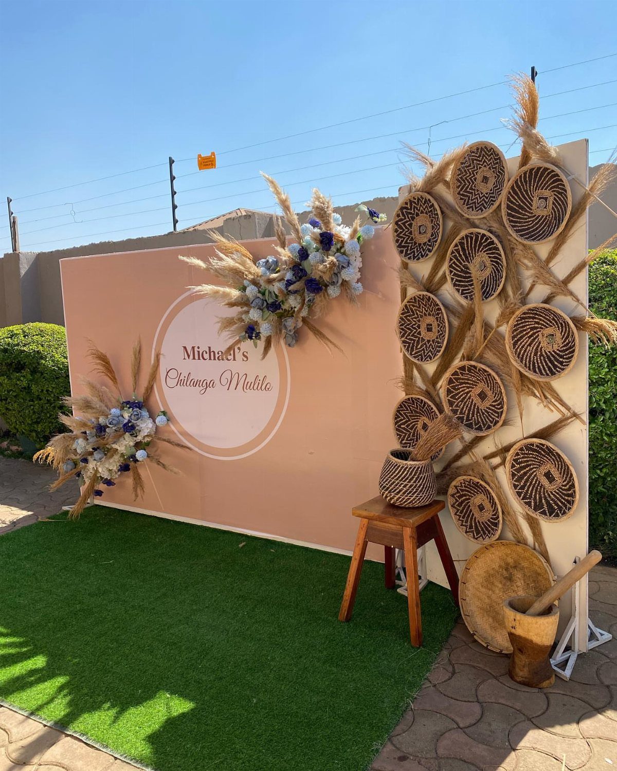 15 Small Wedding Ideas for 50 Guests, From Backyards to Parks 3 Decorative photo booth backdrop with peach wall, floral arrangements, and woven baskets.