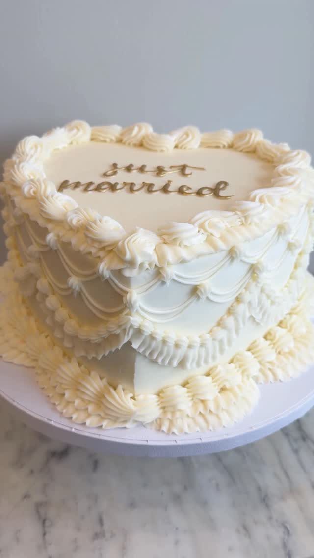 15 Small Wedding Ideas for 50 Guests, From Backyards to Parks 8 Heart-shaped white wedding cake with ornate frosting and gold just married lettering.