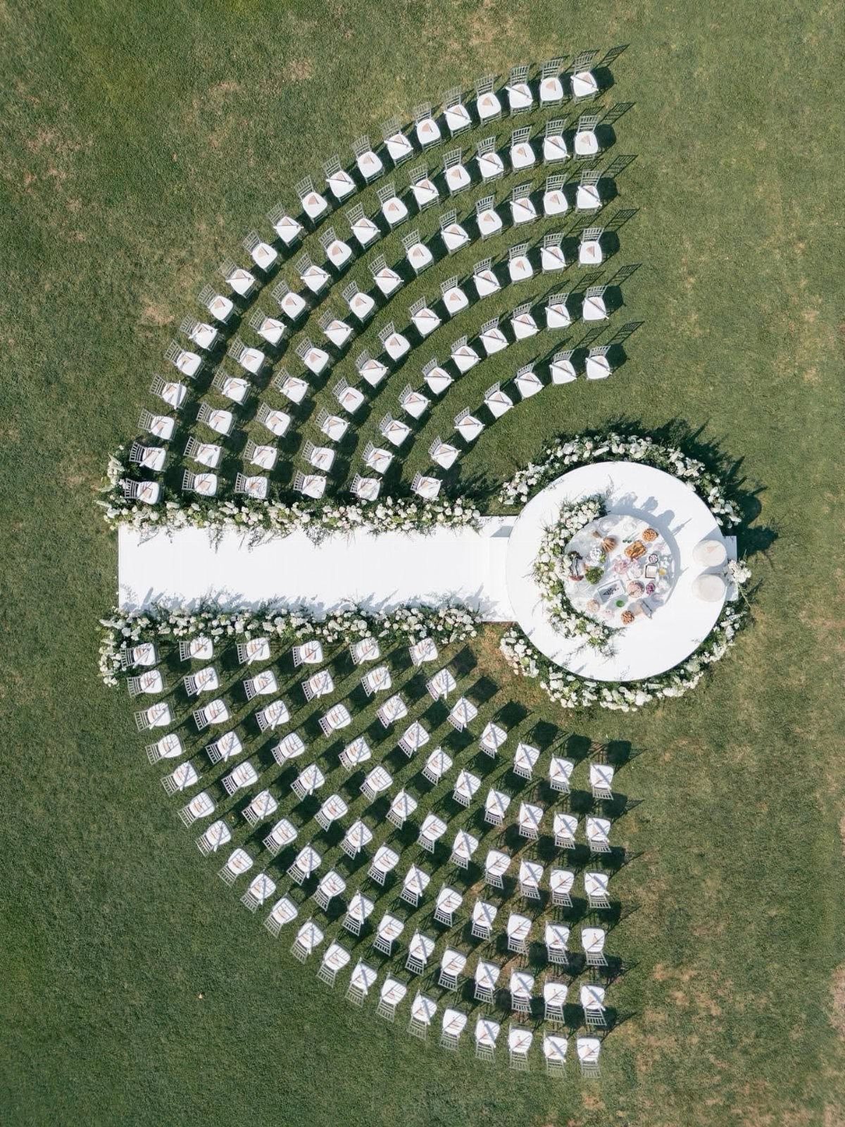13 Small Wedding Party Ideas for an Intimate Celebration 1 White wedding chairs arranged in concentric semi-circles around a circular floral altar platform.