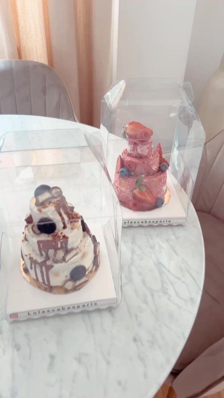 13 Small Wedding Party Ideas for an Intimate Celebration 4 Two small tiered wedding cakes in clear plastic boxes on a marble table.