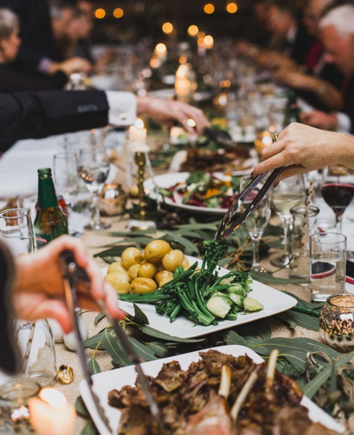 13 Small Wedding Party Ideas for an Intimate Celebration 2 Shared platters of food on a long wedding table with guests serving themselves.