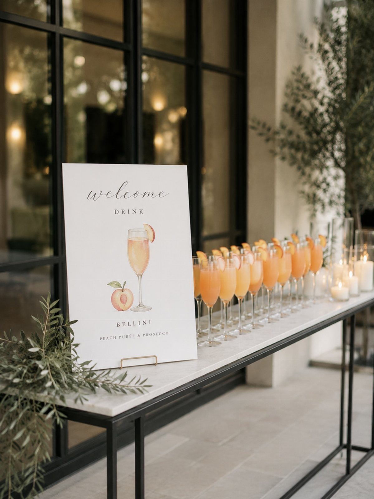 13 Small Wedding Party Ideas for an Intimate Celebration 3 Row of peach Bellini cocktails on a marble table next to a welcome sign.