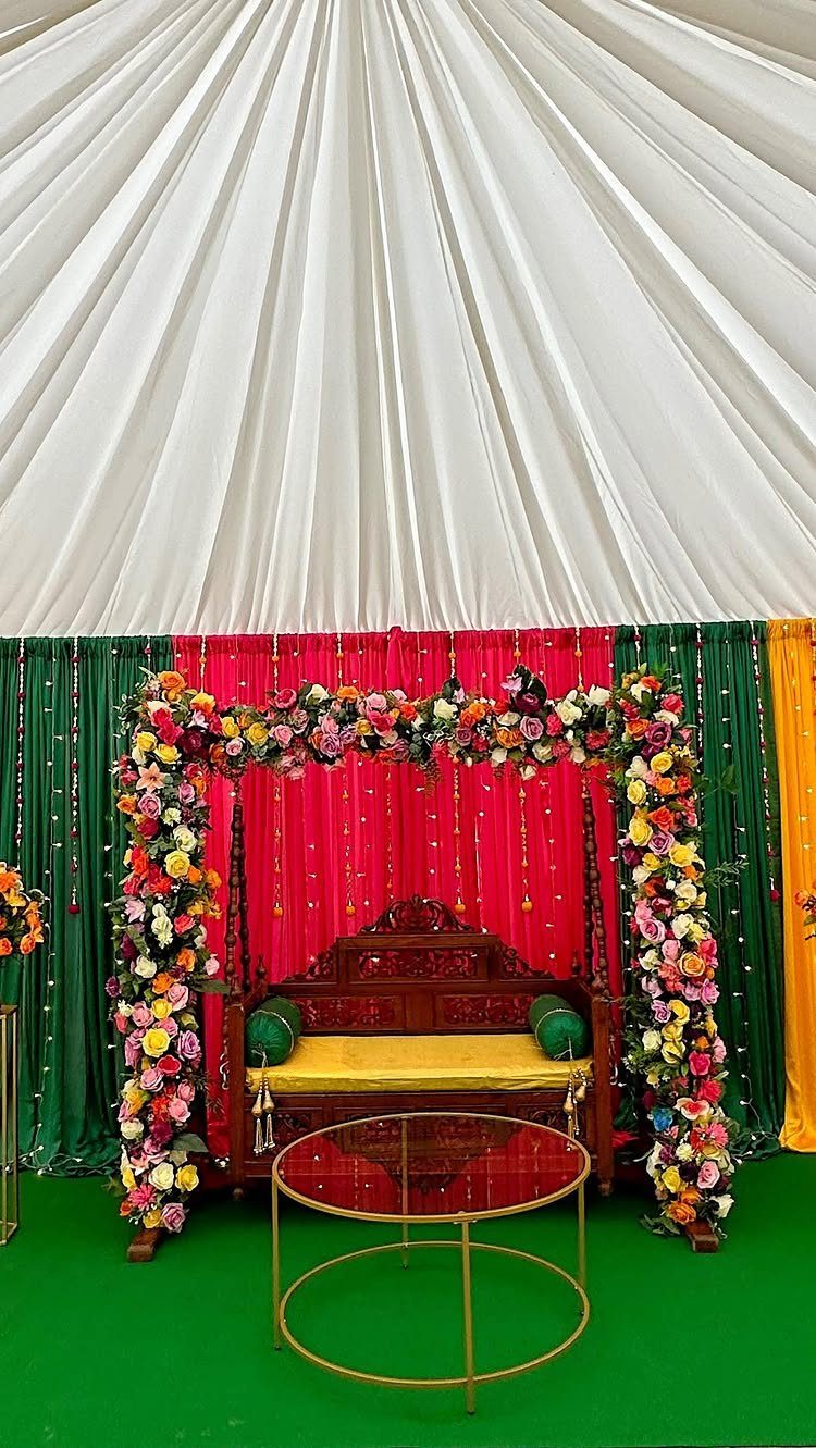 13 Small Wedding Party Ideas for an Intimate Celebration 6 Floral arch and colorful fabric backdrop with a carved wooden bench and gold table.