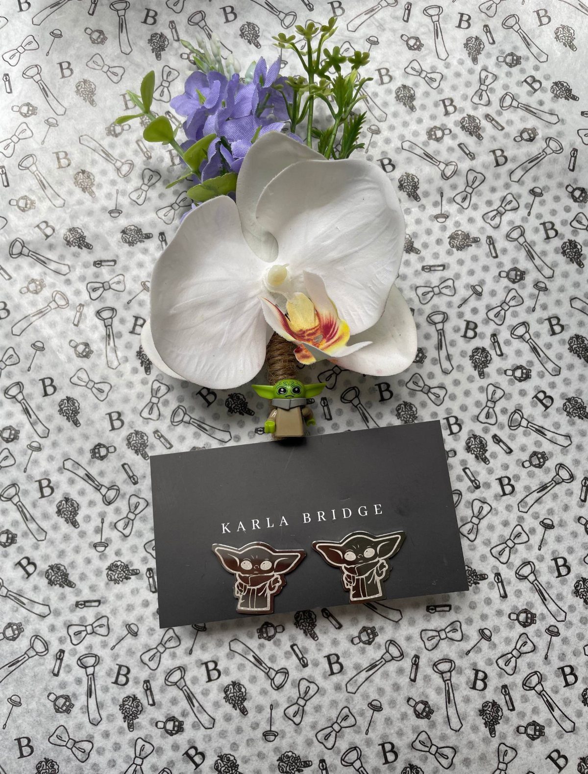 Star Wars themed wedding boutonniere with white orchid and Grogu figure and cufflinks.