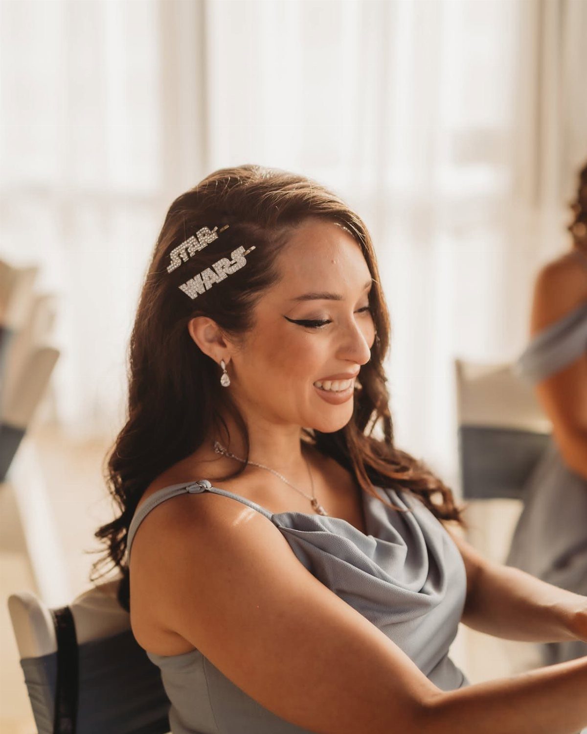 Woman in blue dress wearing a Star Wars logo hair clip and smiling.