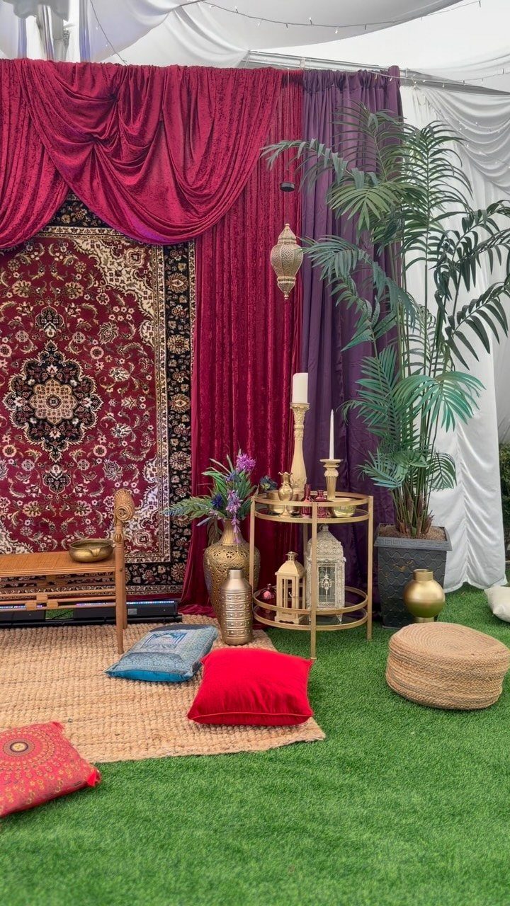 16 Tent Wedding Ideas for Lighting, Tables and Cozy Corners 5 Lounge area with red draped fabric, floor cushions, and a gold candle table.