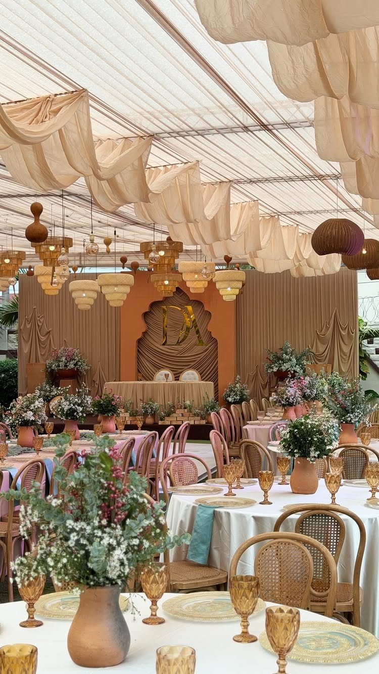 16 Tent Wedding Ideas for Lighting, Tables and Cozy Corners 10 Wedding reception inside a tent featuring draped fabric and various hanging lamps over tables.