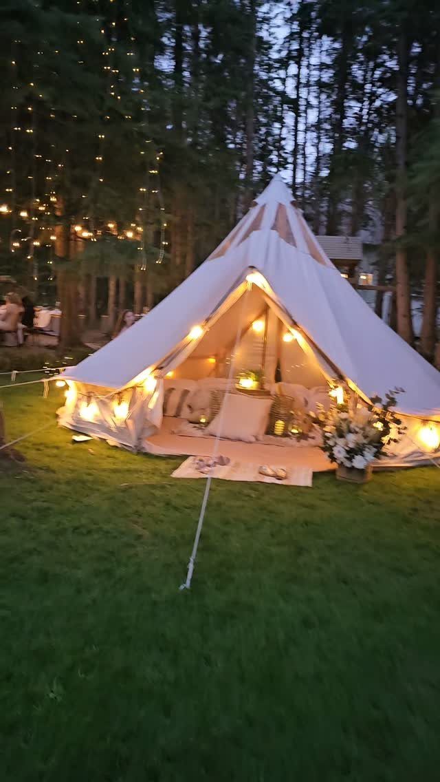 16 Tent Wedding Ideas for Lighting, Tables and Cozy Corners 8 White bell tent with warm lighting and floral arrangements on a grassy lawn