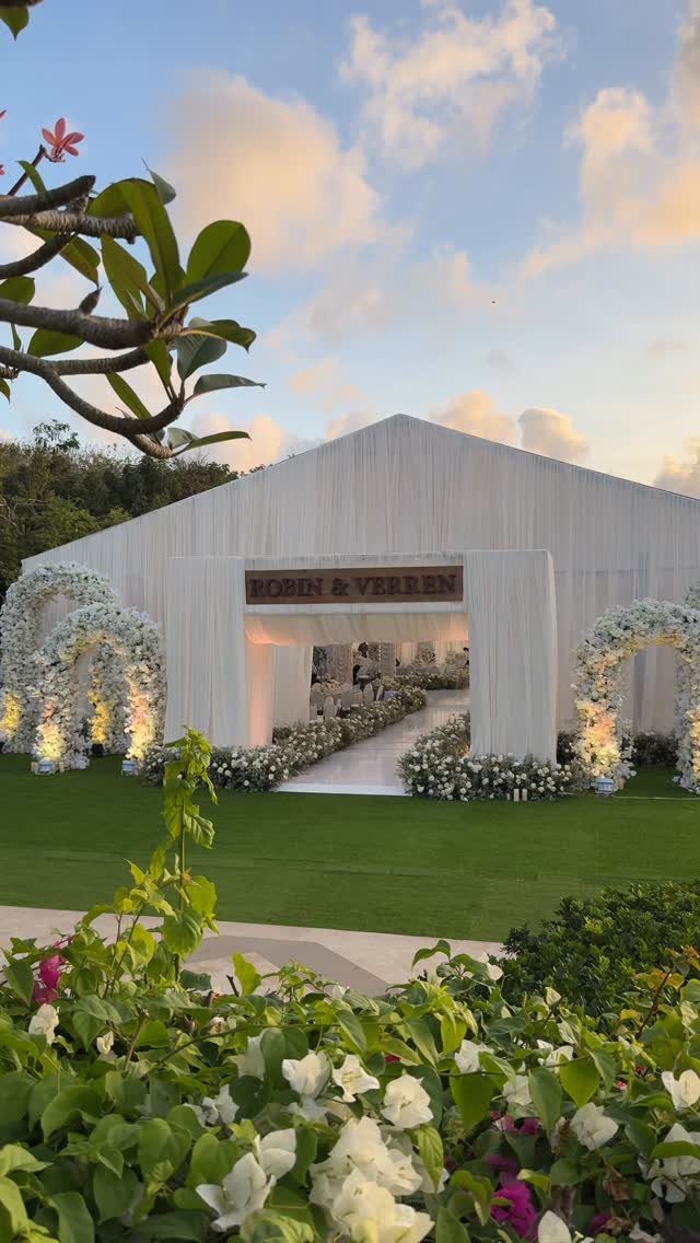 16 Tent Wedding Ideas for Lighting, Tables and Cozy Corners 2 White wedding tent entrance with floral arches and a personalized name sign.