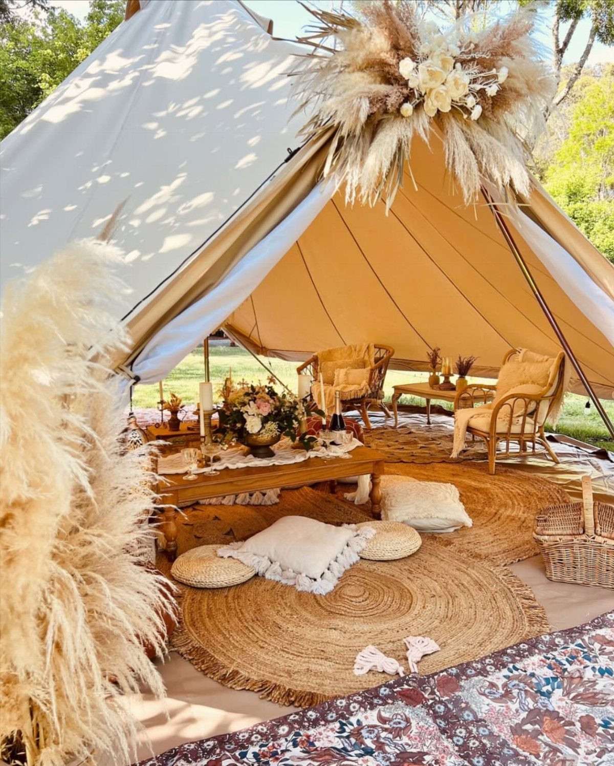 16 Tent Wedding Ideas for Lighting, Tables and Cozy Corners 7 Low wooden table with floral centerpieces inside a decorated beige canvas bell tent