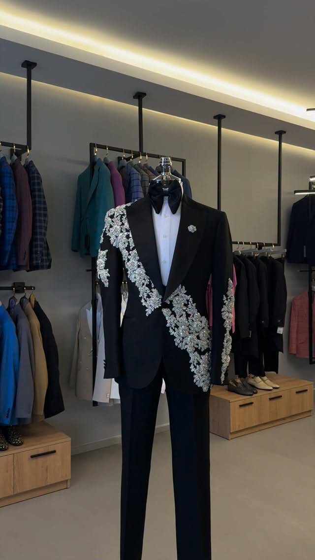 9 Uncommon Wedding Colors for Couples Who Skip the Usual 4 Black tuxedo with silver floral embroidery displayed on a mannequin in a store