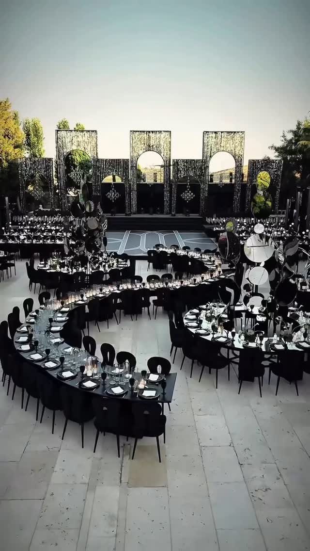 9 Uncommon Wedding Colors for Couples Who Skip the Usual 9 Black and white wedding reception setup with curved tables and decorative floral arches.