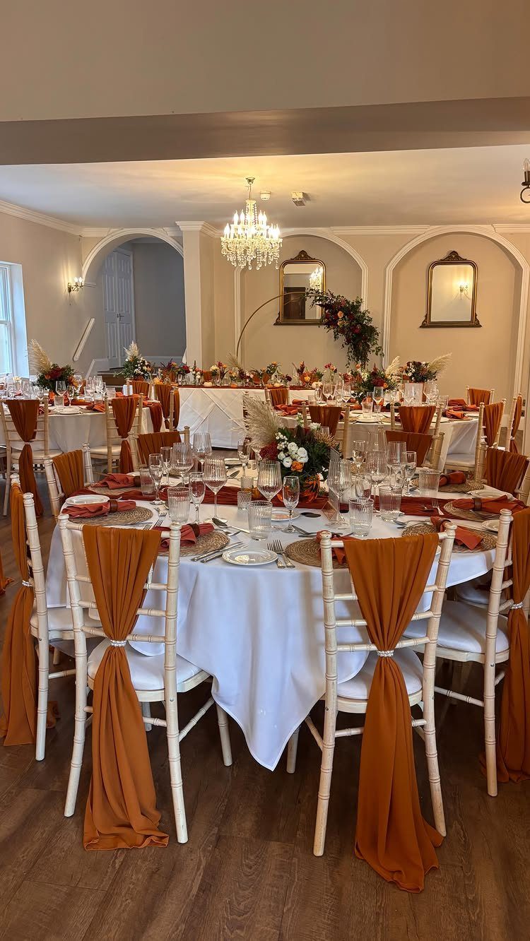 9 Uncommon Wedding Colors for Couples Who Skip the Usual 1 Wedding reception tables with white linens and burnt orange chair sashes and napkins.