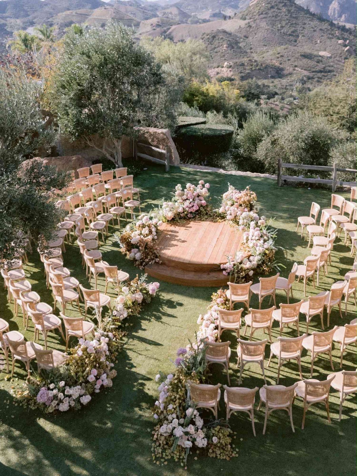 Circular wooden wedding altar with floral arrangements and curved rows of wooden chairs.
