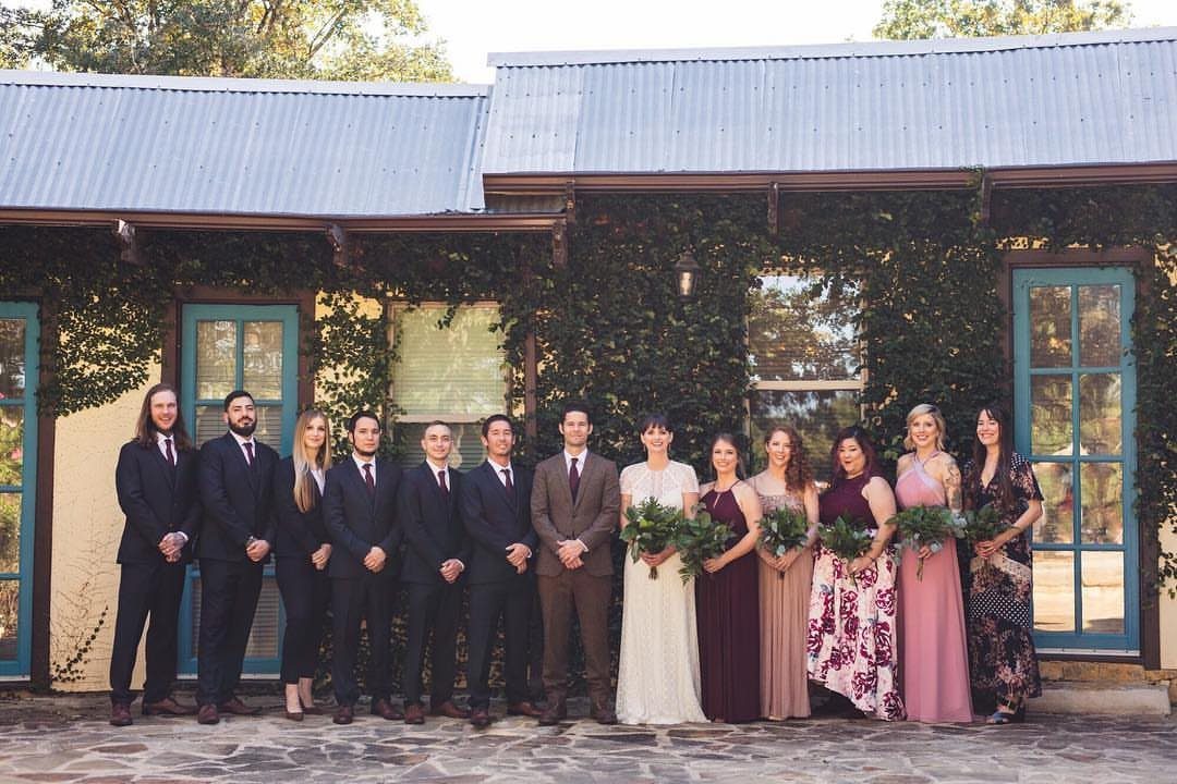 Wedding party posing in a line with an uneven number of bridesmaids and groomsmen.