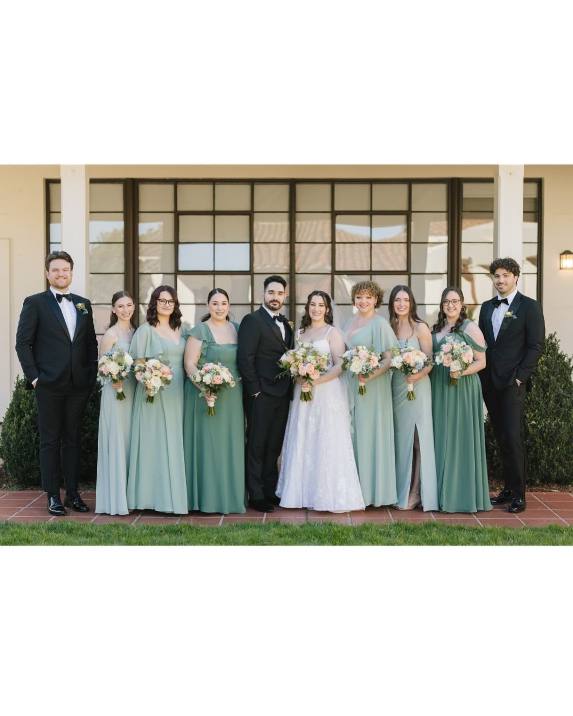 Wedding party posing with an uneven number of bridesmaids and groomsmen outdoors.