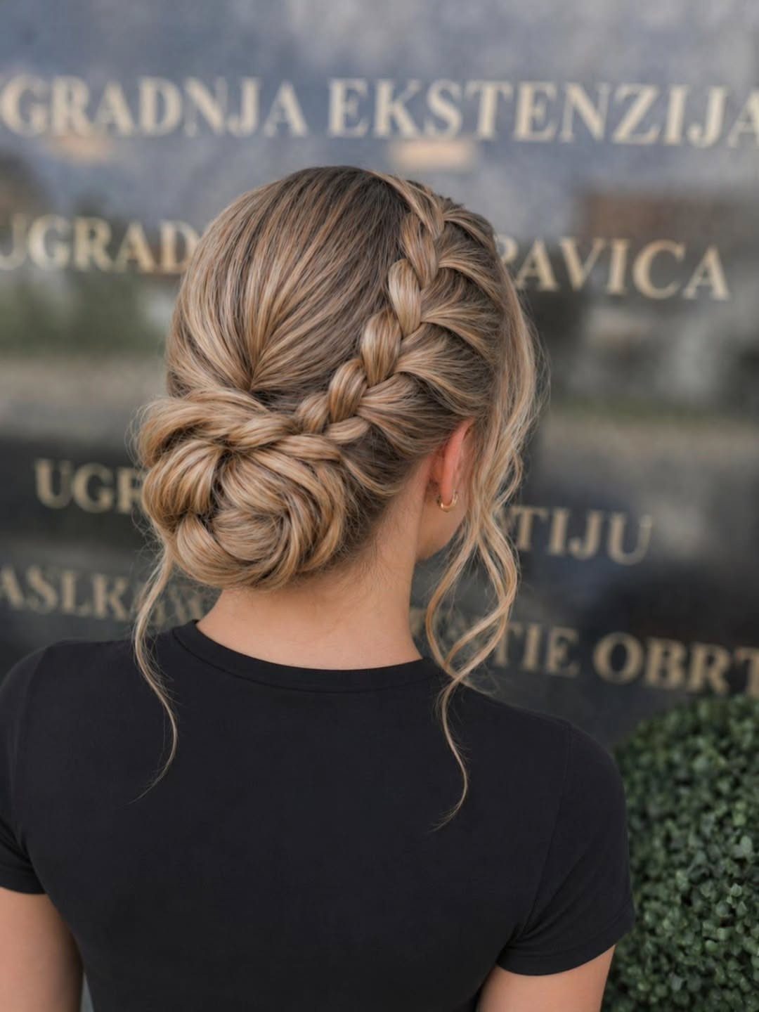 Blonde hair styled in a braided low bun with loose face-framing strands.