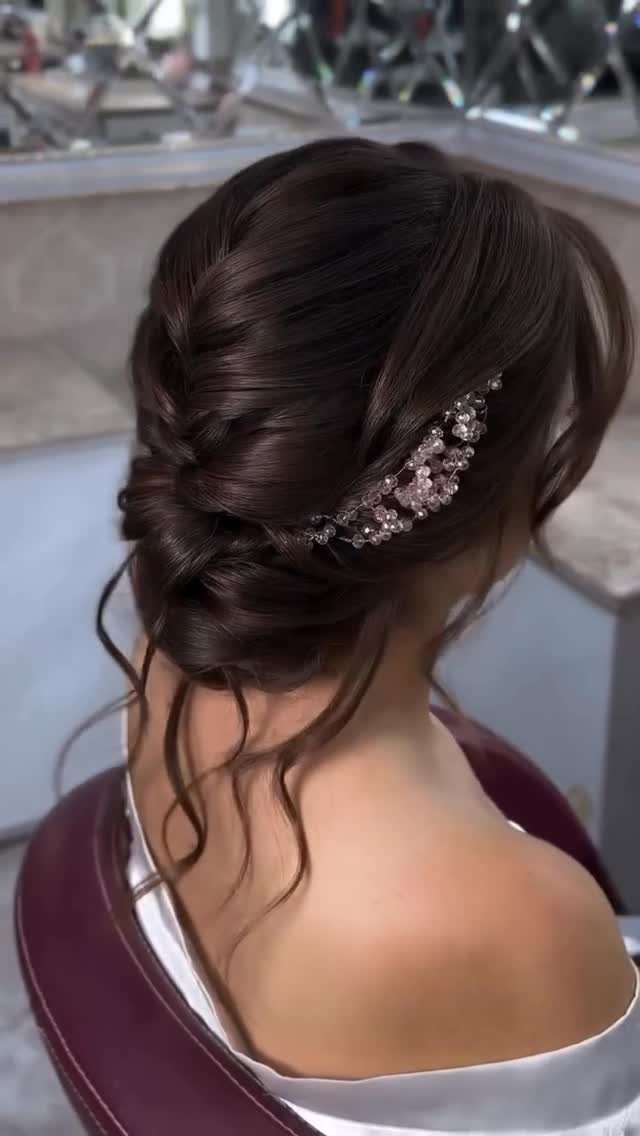 Low textured bun with a braid and sparkling floral hair accessory on brown hair