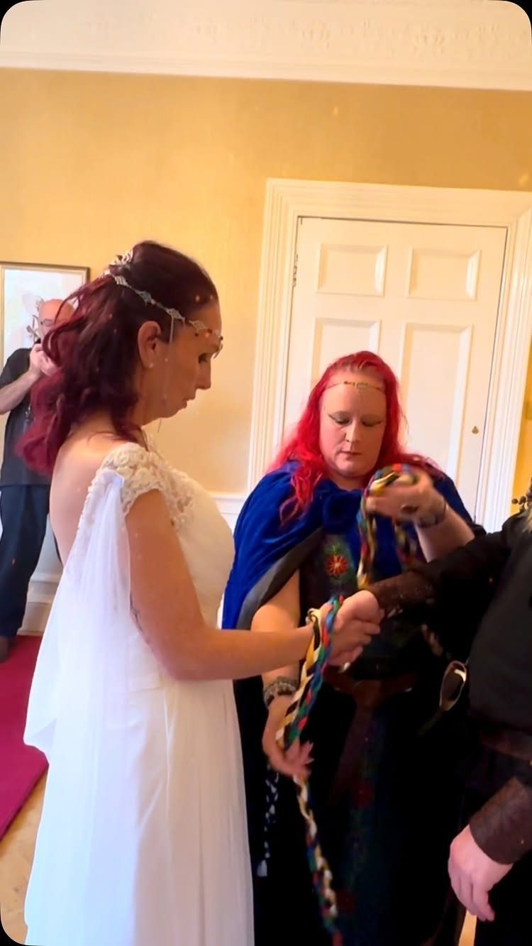 Handfasting ceremony with a colorful braided cord binding a couple's hands together.