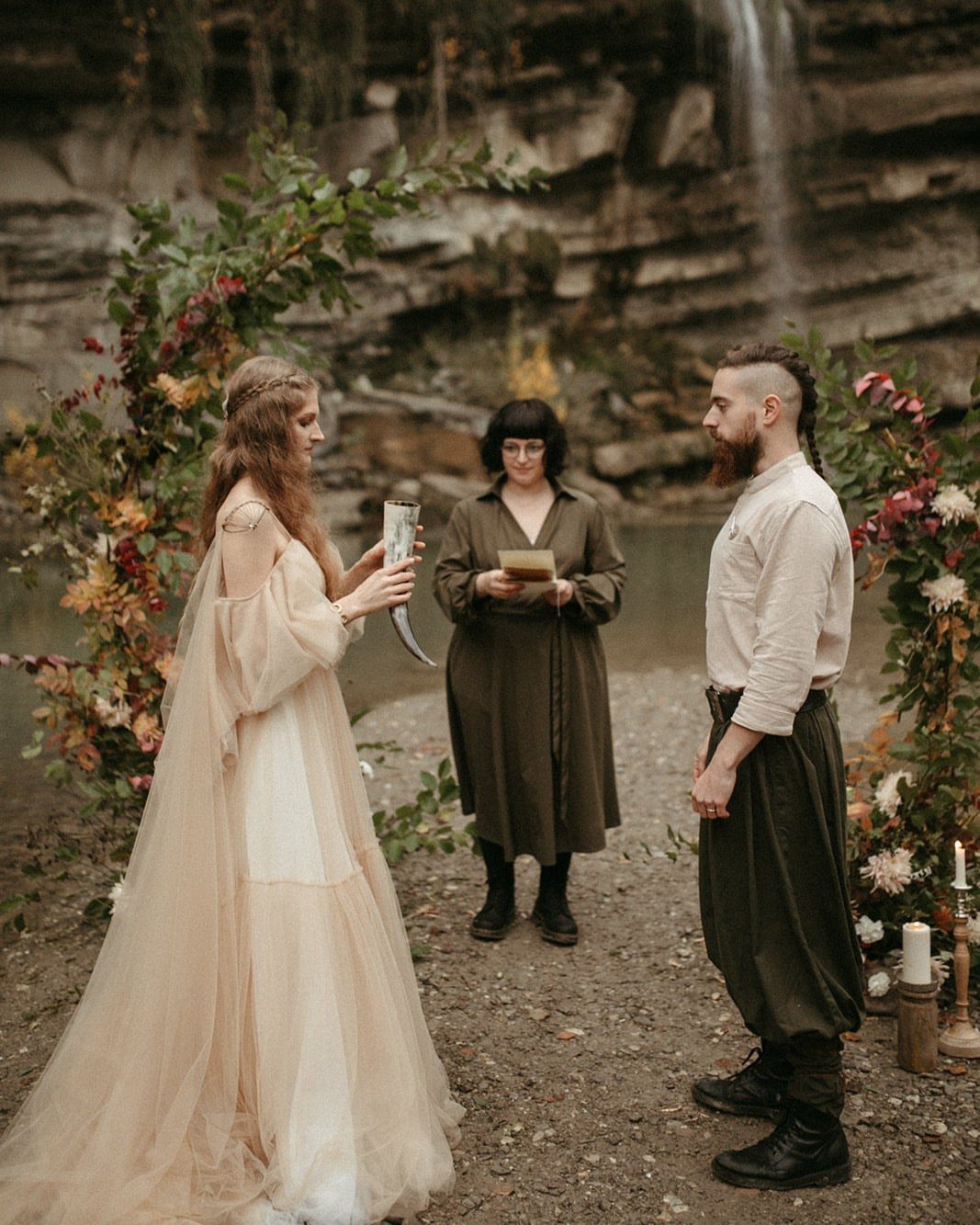 Woman in beige gown holding a drinking horn during a Viking wedding ceremony.