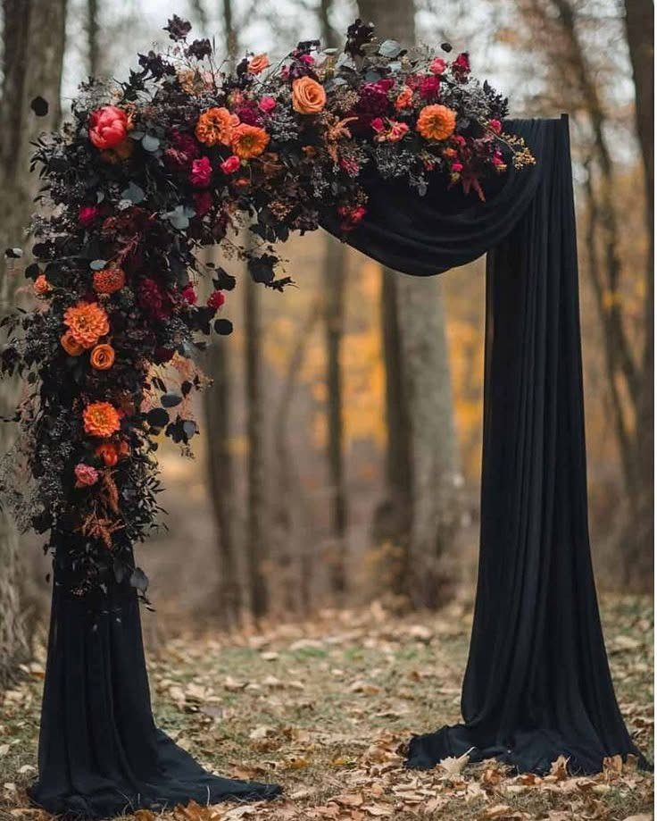 Wedding arch with black fabric and autumn flowers in a wooded forest setting