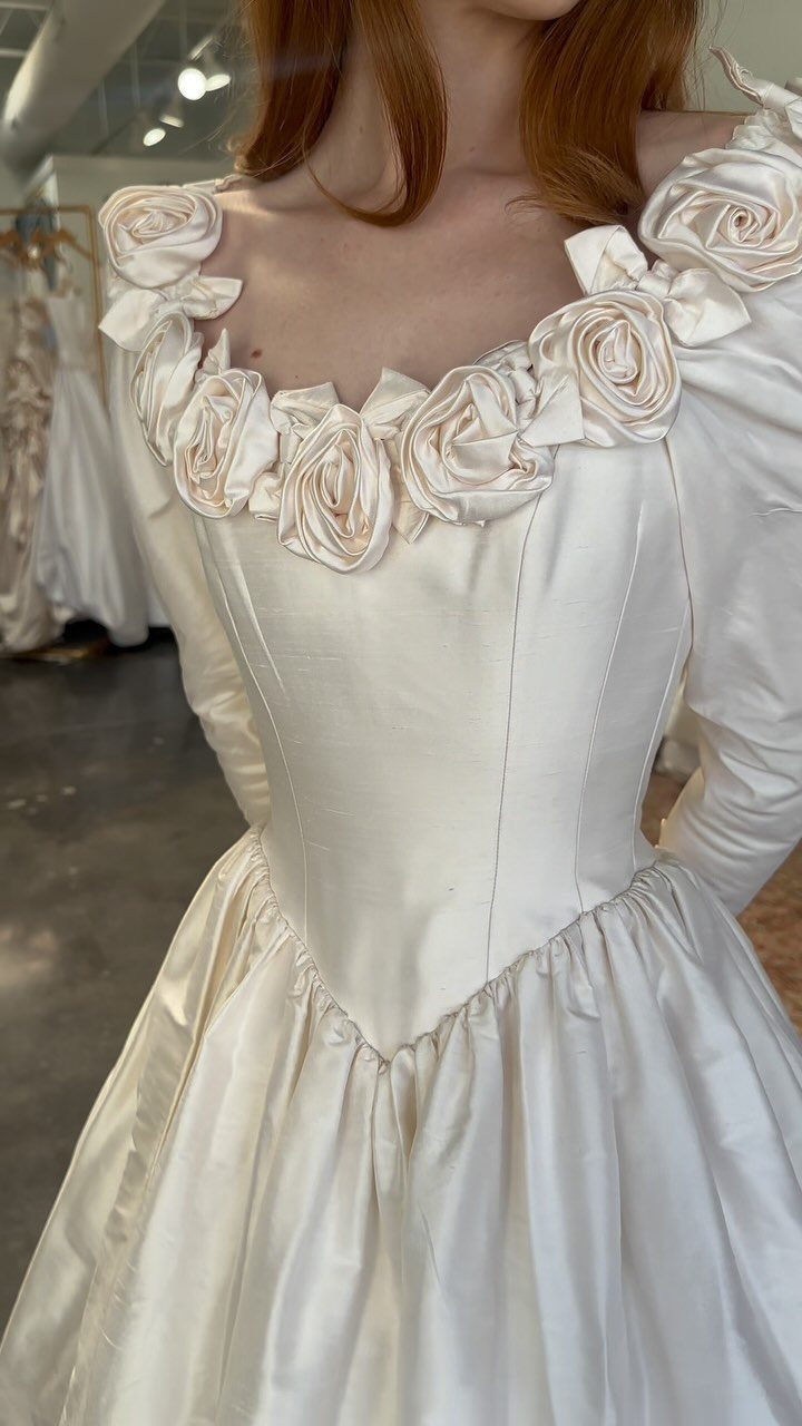 9 Ideas for a Vintage Basque Waist Wedding Dress 2 White satin wedding dress featuring a V-shaped basque waist and fabric rose neckline.