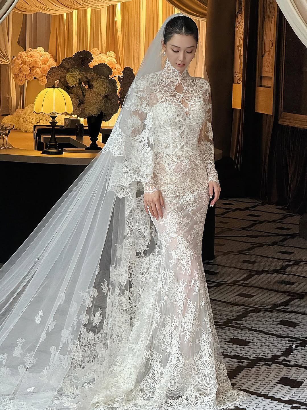 Vintage Chanel Wedding Dress Ideas: 8 Bridal Looks 4 Woman in a high-neck white lace wedding dress with a long sheer veil.
