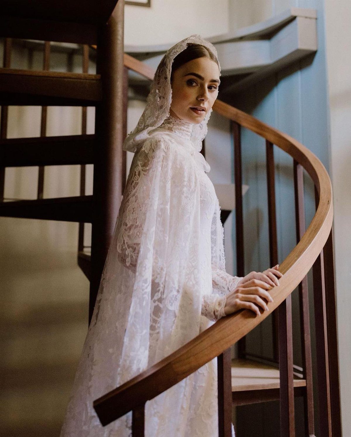 Vintage Chanel Wedding Dress Ideas: 8 Bridal Looks 1 Woman in a white lace wedding dress and veil on a wooden staircase