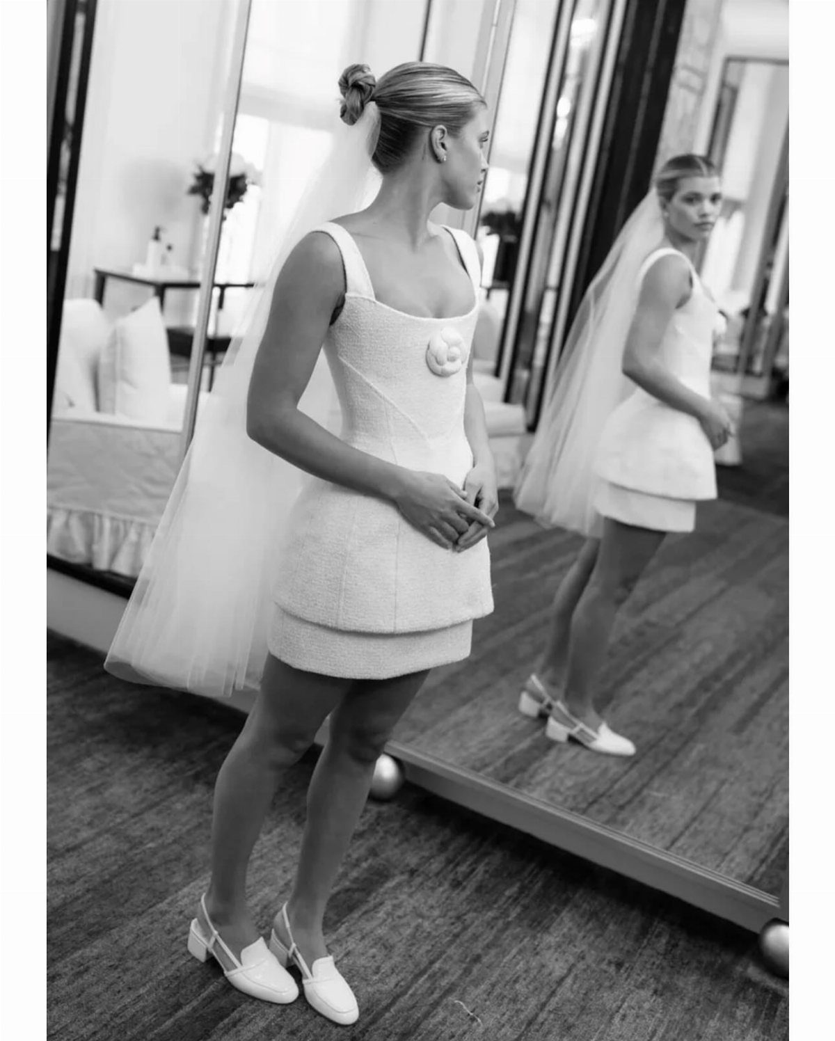 Vintage Chanel Wedding Dress Ideas: 8 Bridal Looks 3 Woman wearing a short white Chanel bridal dress and veil standing by a mirror.