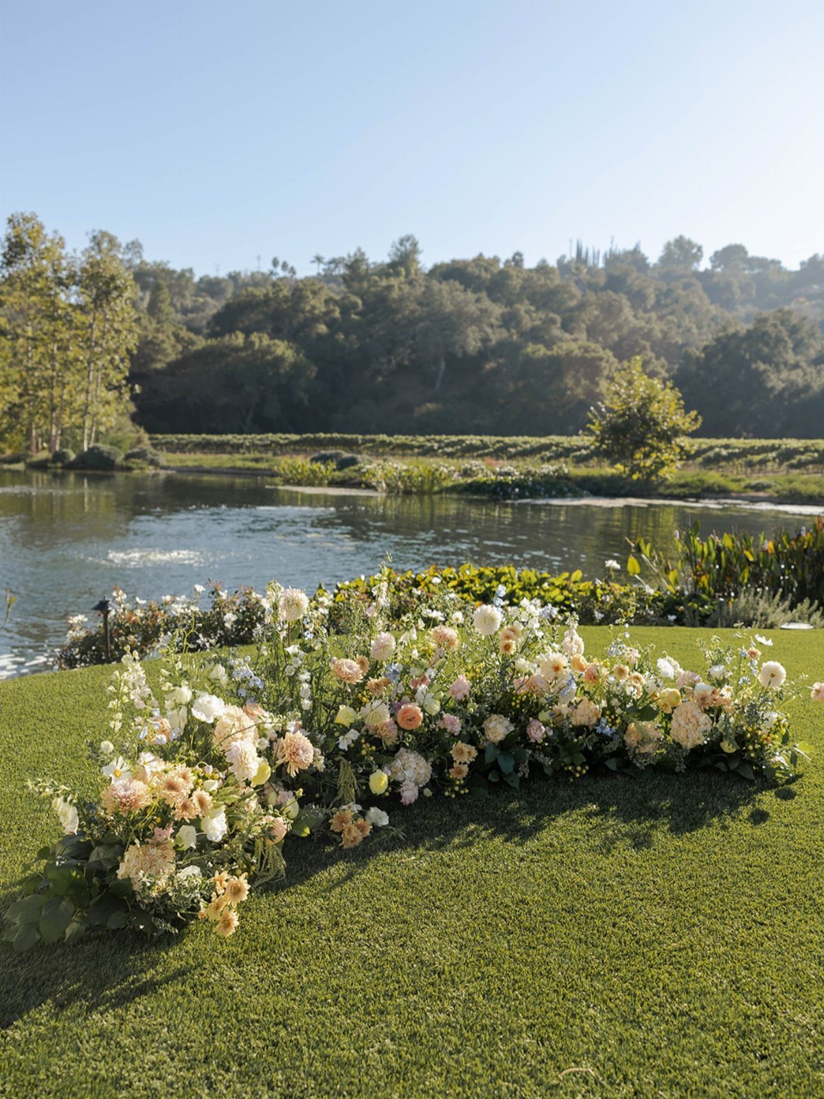 5 Wedding Arch Without Flowers Ideas for Your Ceremony 2 Floral clusters of peach and white flowers arranged on a green grass lawn.
