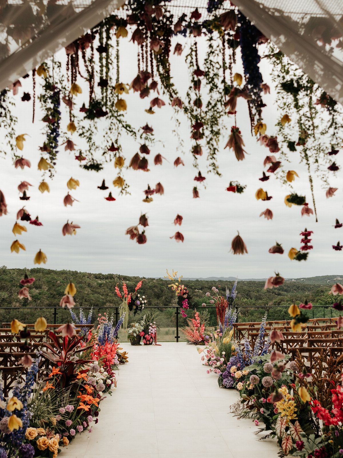 5 Wedding Arch Without Flowers Ideas for Your Ceremony 4 Hanging floral installations and greenery suspended from a white canopy over a wedding aisle.
