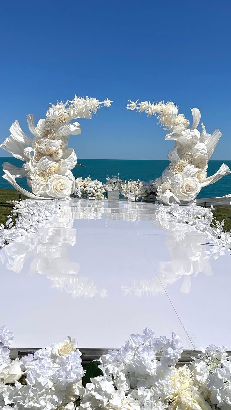 5 Wedding Arch Without Flowers Ideas for Your Ceremony 5 White circular wedding arch made of large paper flowers on a reflective white floor.