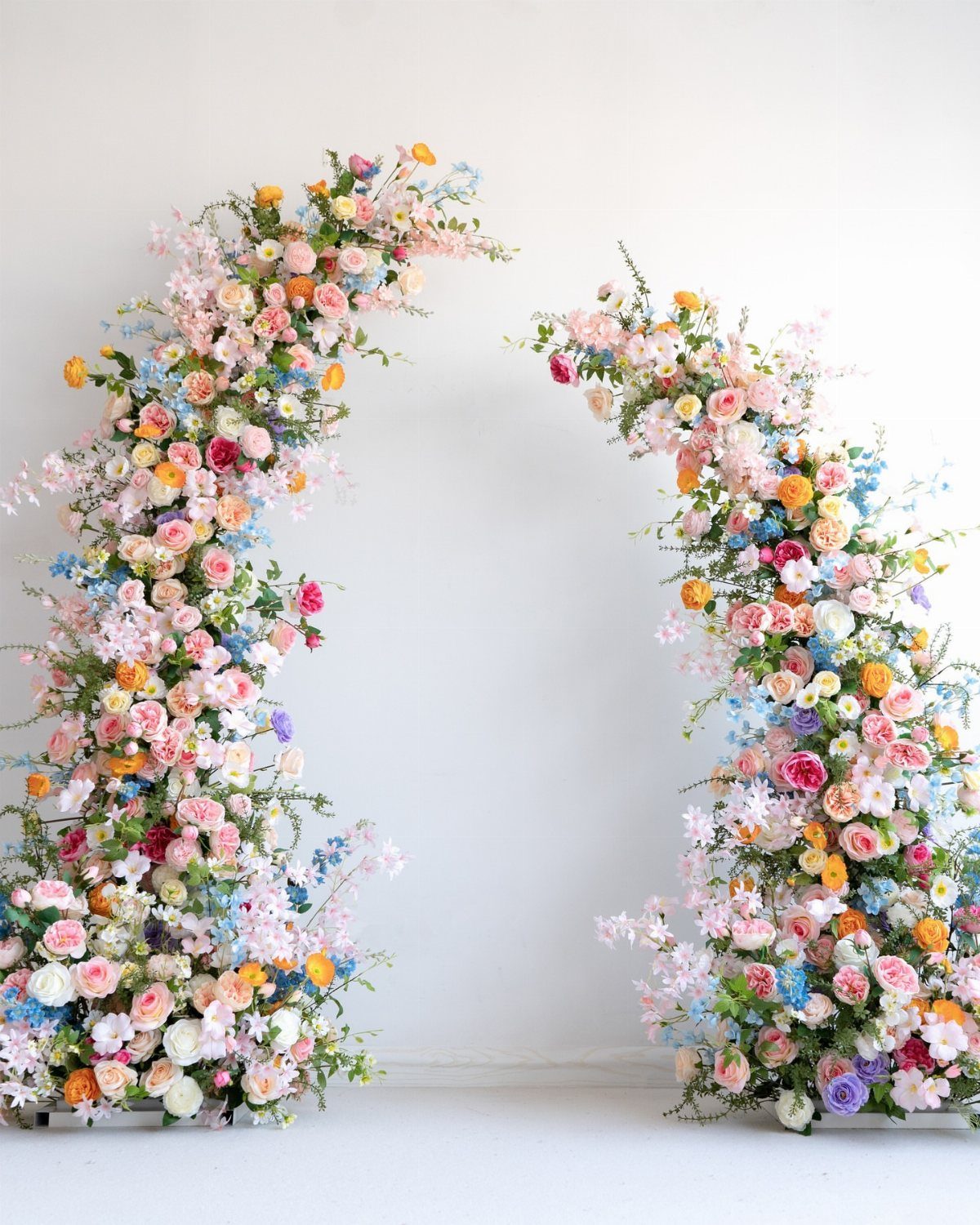 19 Wedding Backdrop Decorations for Any Ceremony Style 16 Two colorful floral pillars with pink and blue roses against a white wall